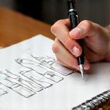 Person sketching cosmetic bottle ideas on paper